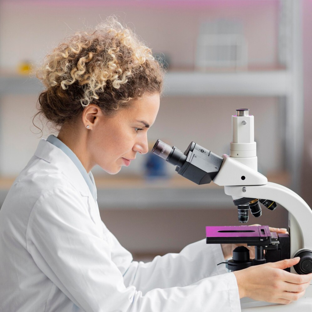 Female scientist examining a sample under a microscope in a laboratory, participating in hands-on training on botulinum toxin research and medical applications.