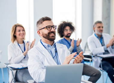 Doctors and medical professionals applauding at a conference, engaging in networking and collaboration.